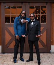 Load image into Gallery viewer, Two men in formal suits standing in front of a wooden door.