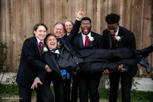 Load image into Gallery viewer, Group of men in suits posing for a photo against a wooden fence.