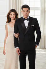 Load image into Gallery viewer, Man in a black tuxedo and woman in a beige evening gown standing together indoors.